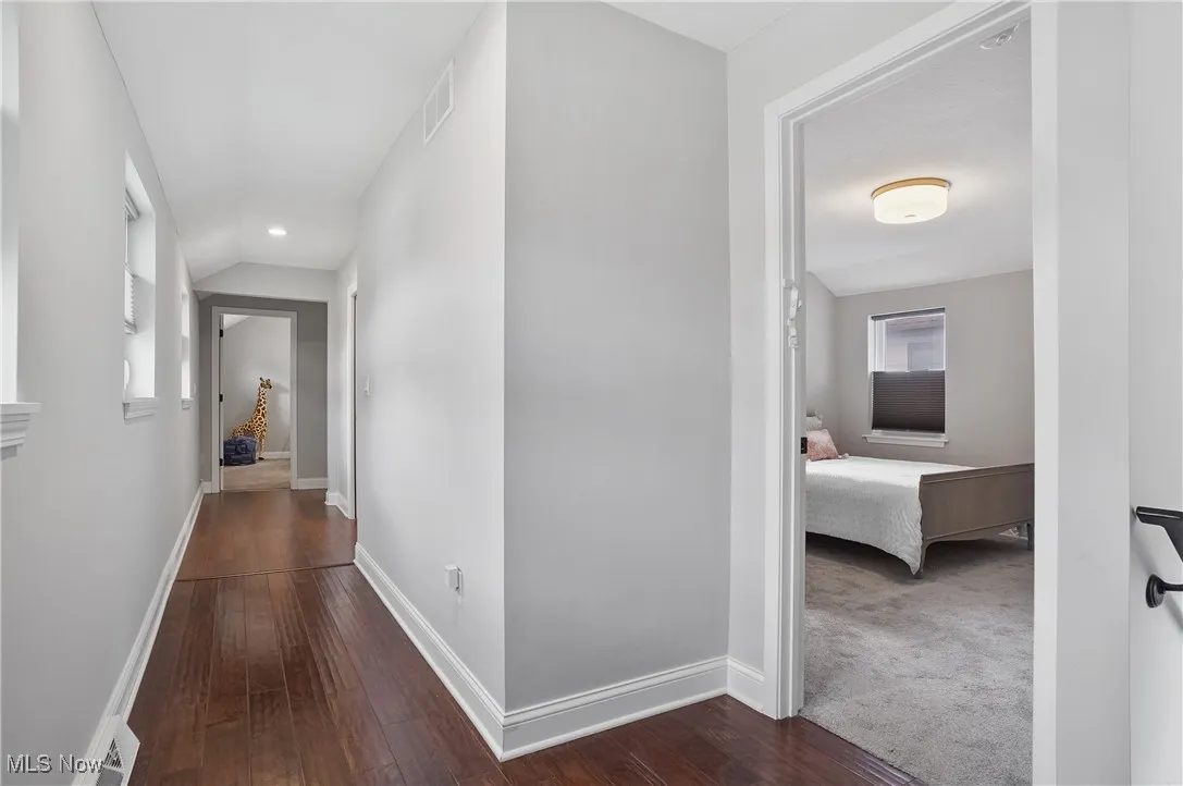 Hallway with dark wood-style floors, recessed lighting, and vaulted ceiling
