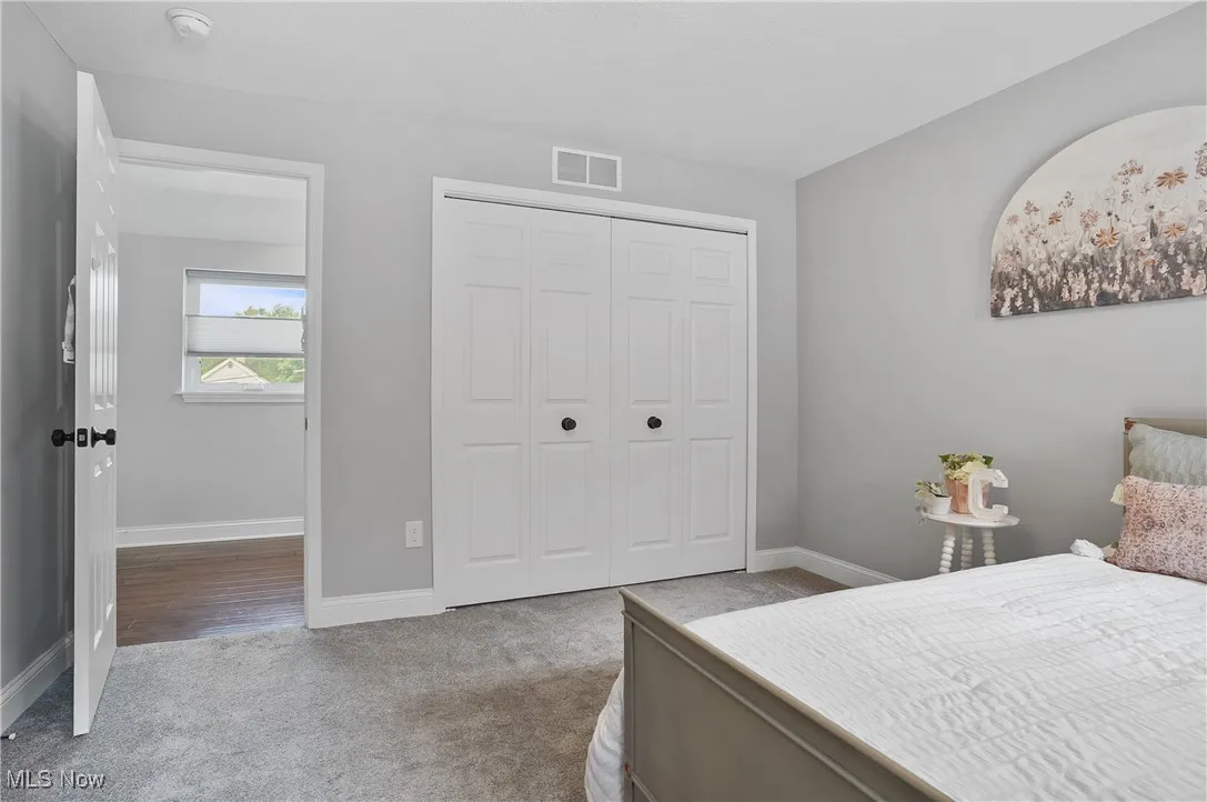 Bedroom with light colored carpet and a closet