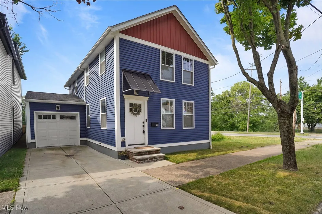 View of front of property featuring concrete driveway, a front lawn, and a garage
