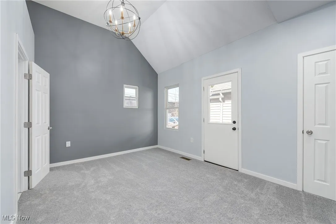 Empty room with an inviting chandelier, carpet flooring, visible vents, and baseboards