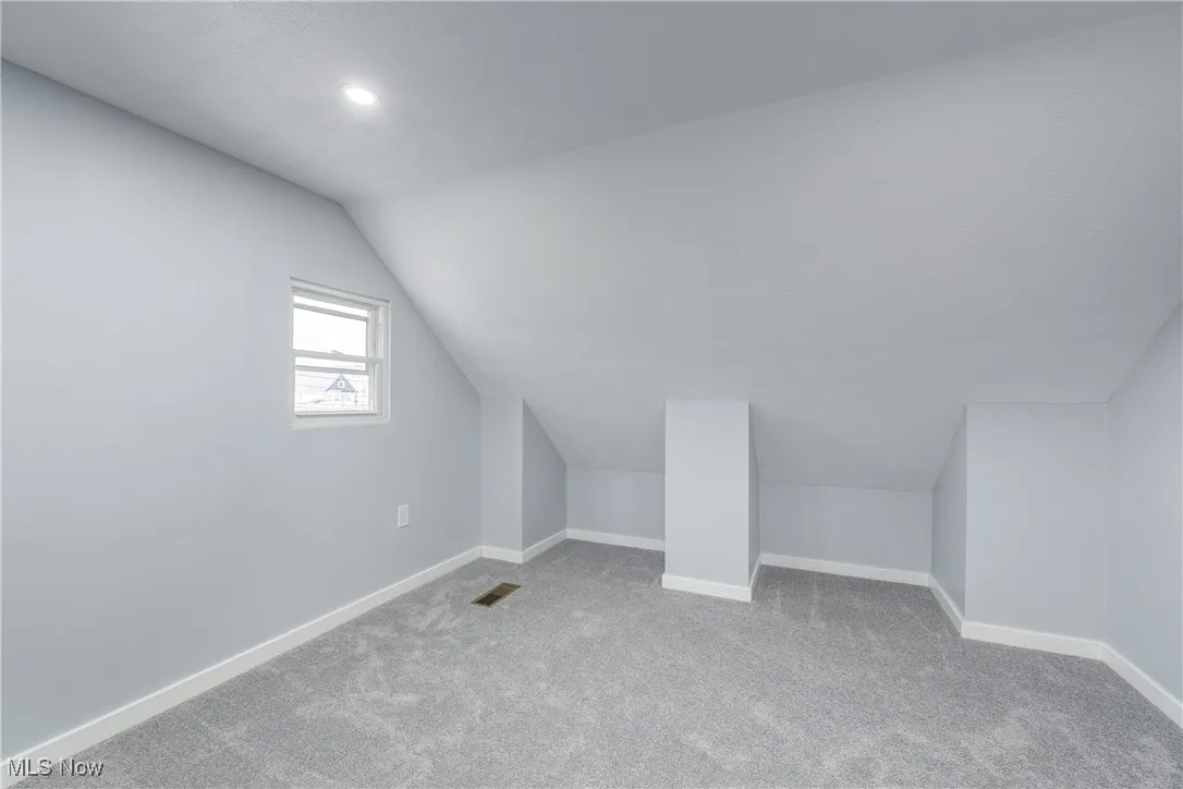 Bonus room with lofted ceiling, carpet flooring, visible vents, and baseboards