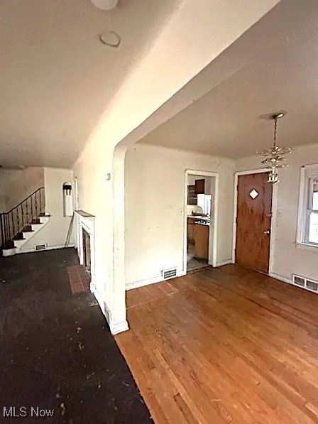Unfurnished living room featuring wood finished floors and stairs
