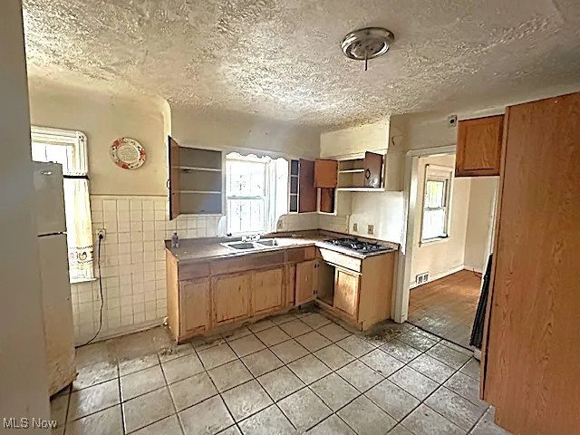 Kitchen featuring tile walls, a textured ceiling, light tile patterned floors, plenty of natural light, and open shelves