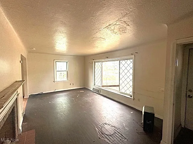 Unfurnished living room with a textured ceiling, a fireplace, and dark wood-style floors