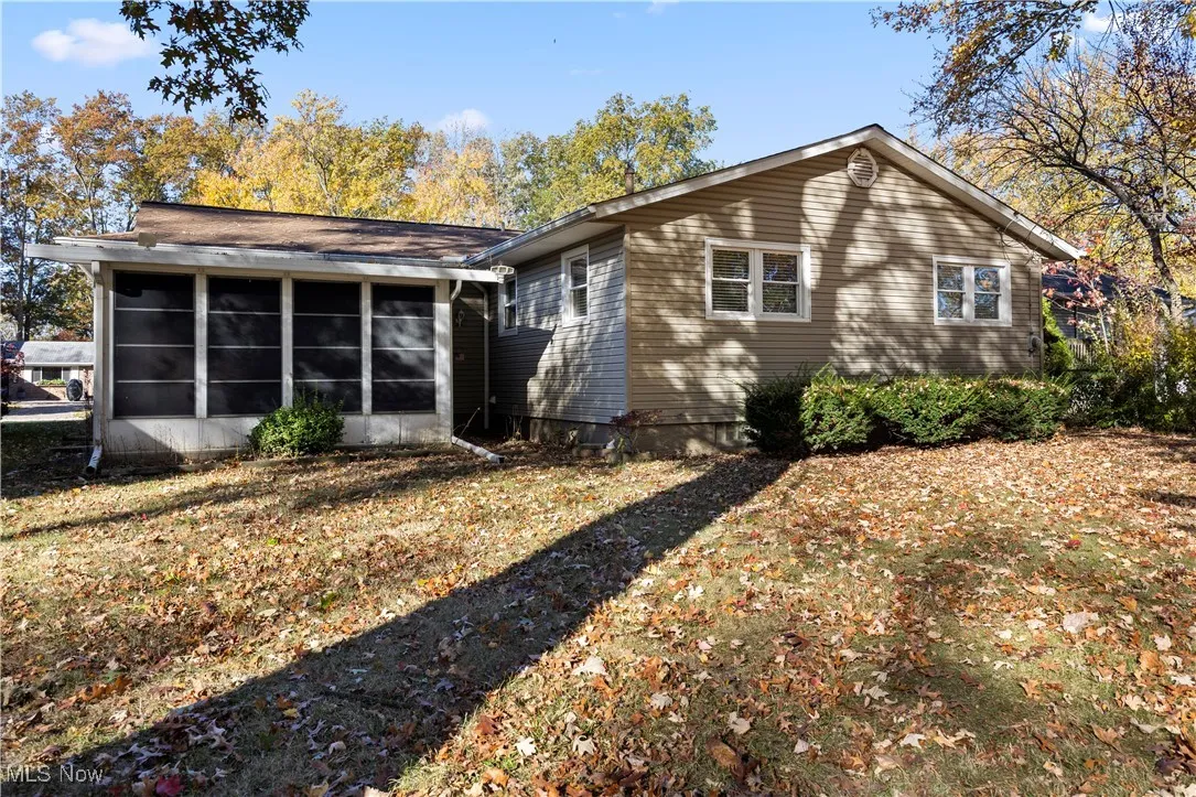 Rear view of house featuring a sunroom and a lawn