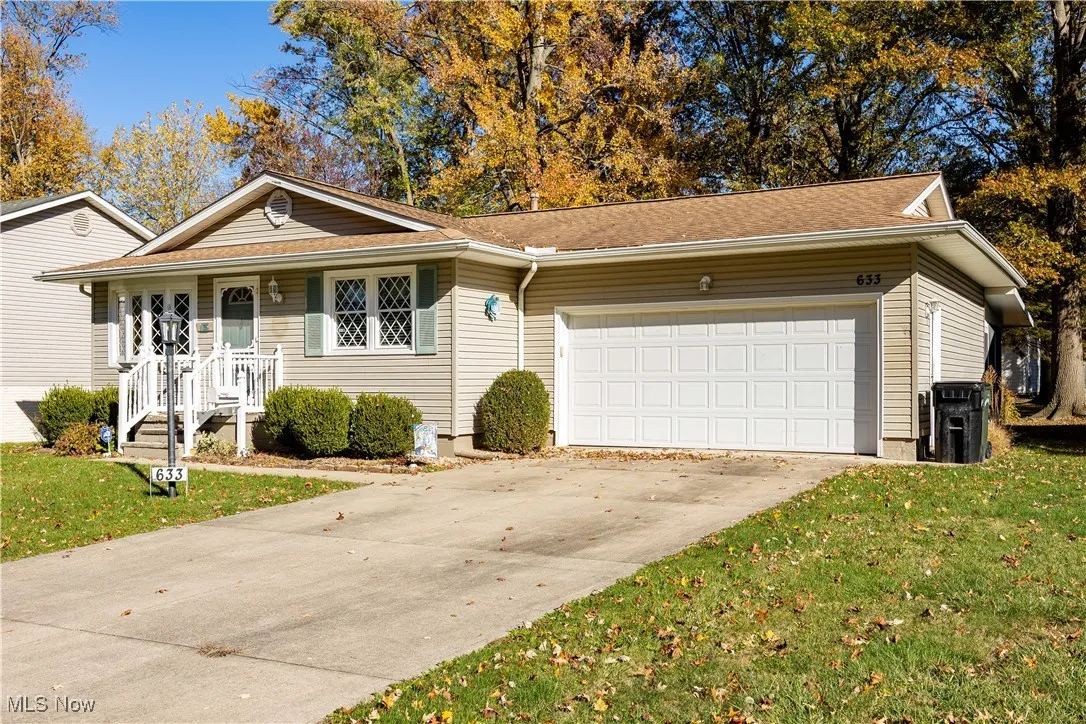 Ranch-style house with a front yard, concrete driveway, a garage, and roof with shingles
