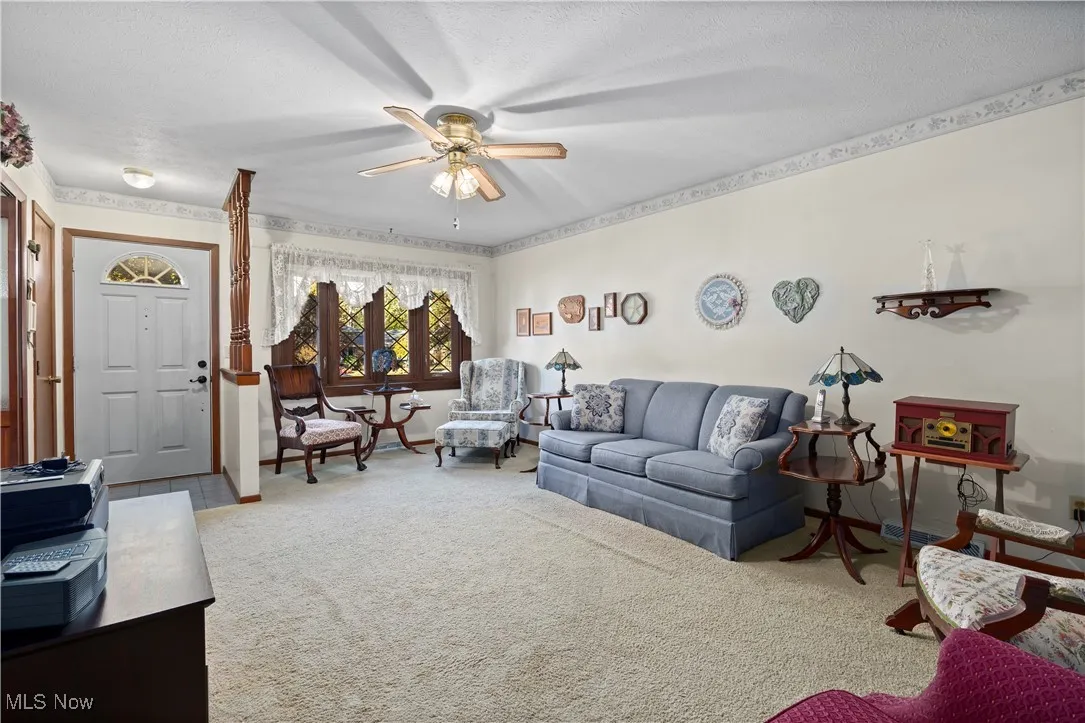 Living room with carpet flooring, ceiling fan, and a textured ceiling