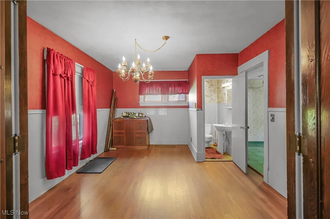 Foyer entrance with light wood-type flooring, a chandelier, and a wainscoted wall