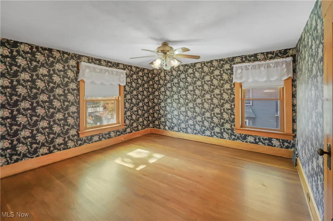 Unfurnished room featuring wood finished floors, wallpapered walls, and ceiling fan