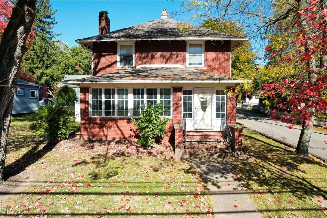 American foursquare style home featuring a chimney and brick siding