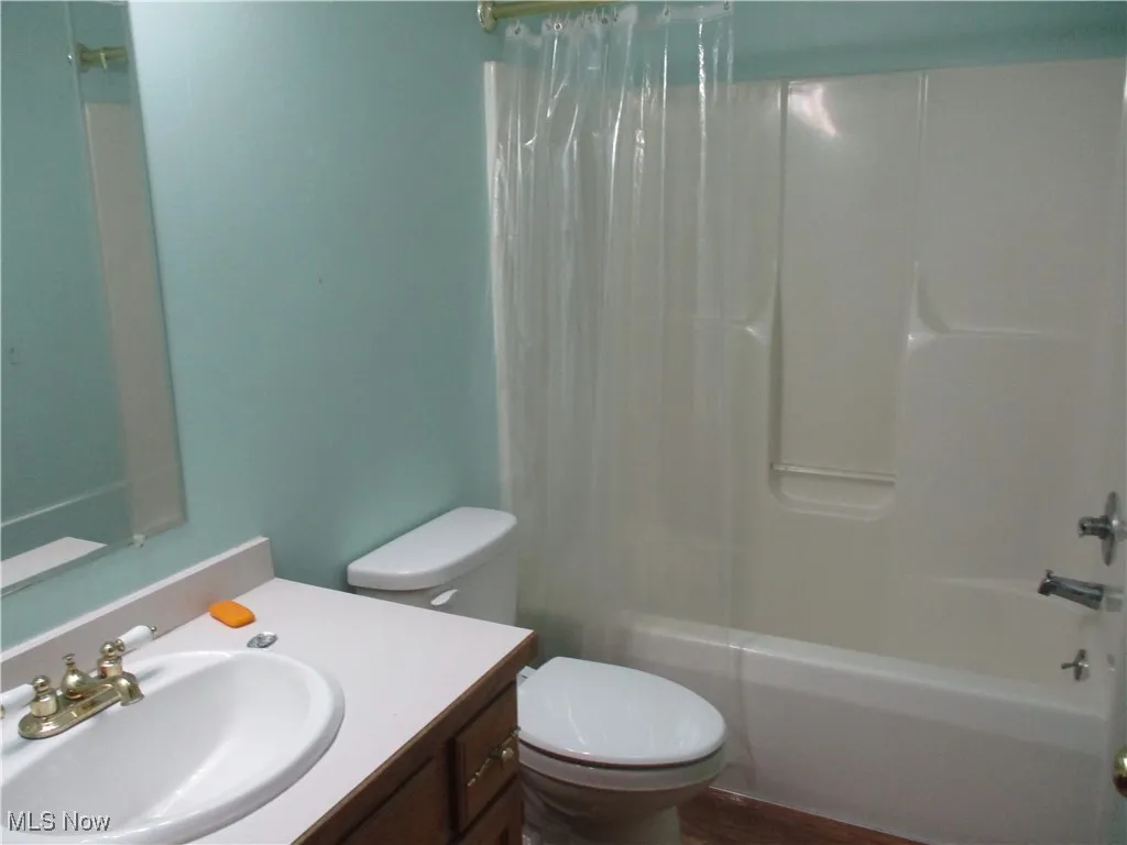 Bathroom featuring vanity, shower / bath combo, and wood finished floors
