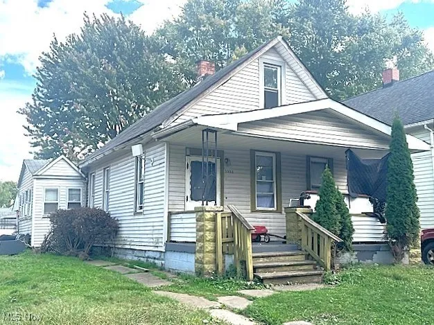 Bungalow-style house with a front lawn, a porch, and a chimney