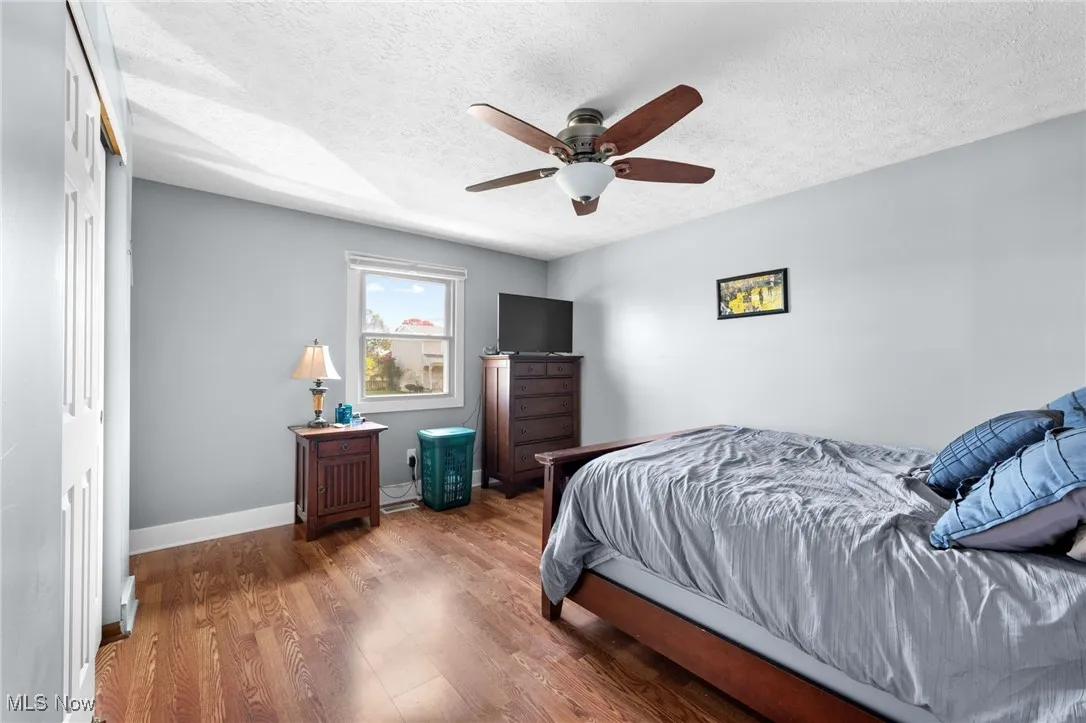 Bedroom featuring wood finished floors, a textured ceiling, and a ceiling fan