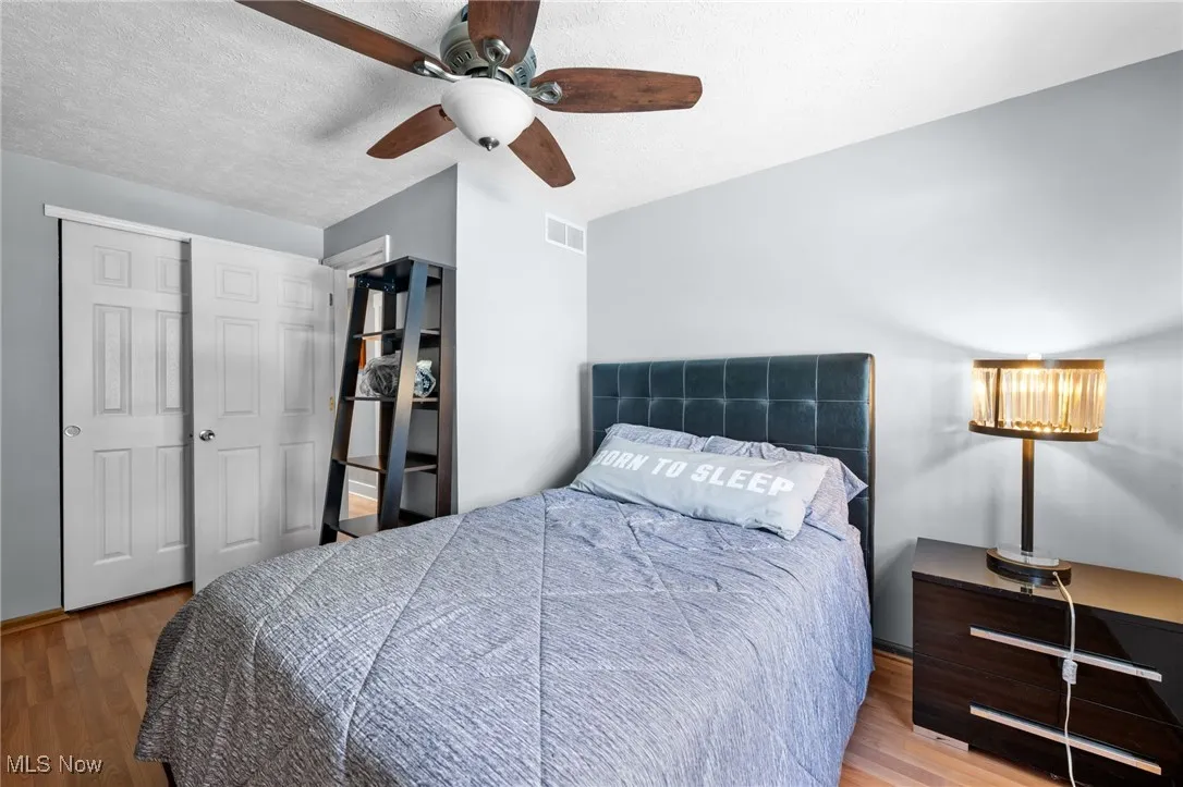 Bedroom featuring light wood-style flooring, ceiling fan, a textured ceiling, and a closet