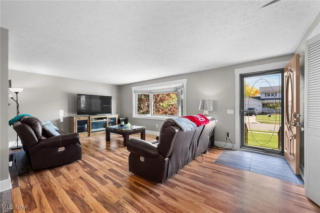 Living area with a textured ceiling, plenty of natural light, and wood finished floors