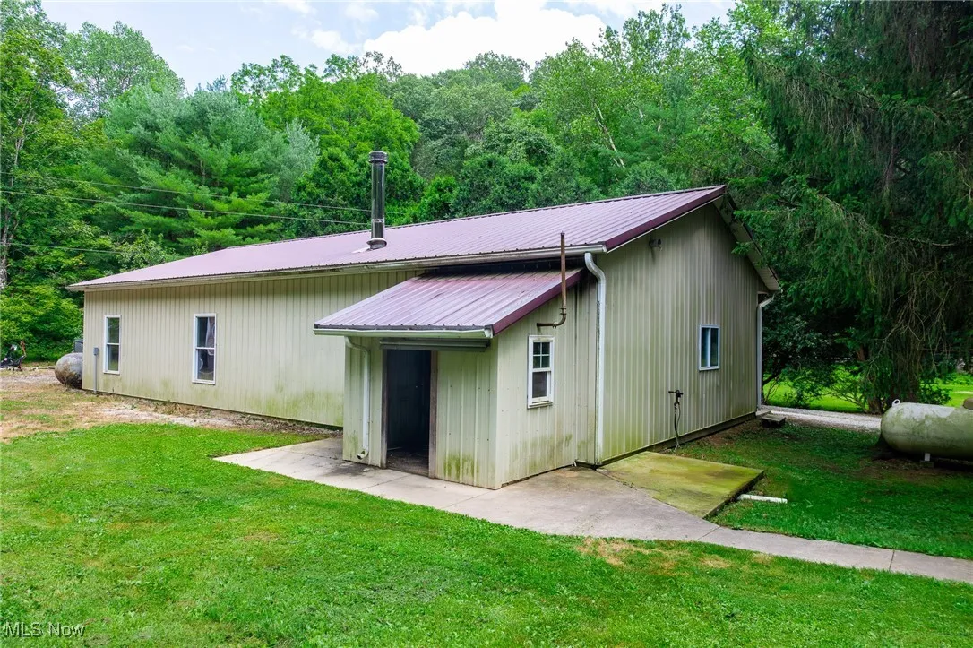 Rear view of property with a metal roof and a lawn