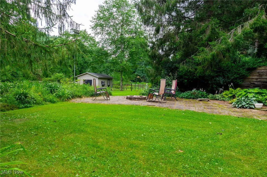 View of yard featuring an outdoor structure, a patio, and an outdoor fire pit