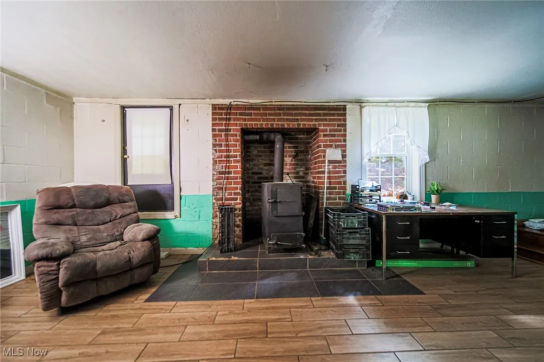 Living area featuring a wood stove, a textured ceiling, and wood tiled floors