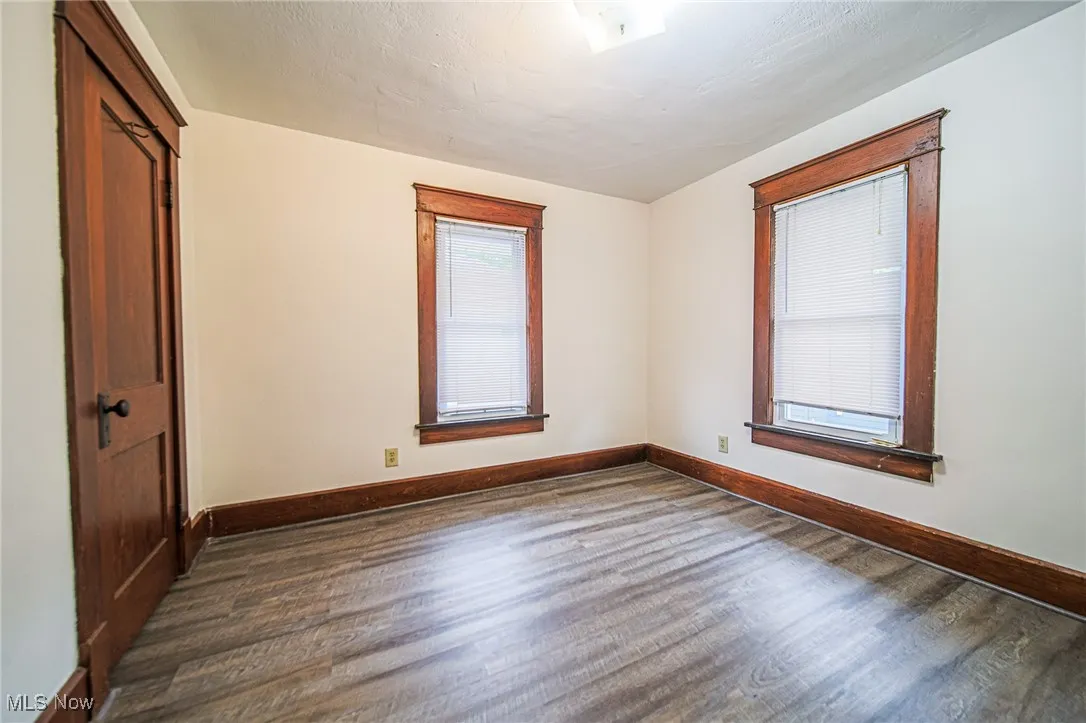 Unfurnished room with dark wood finished floors and baseboards