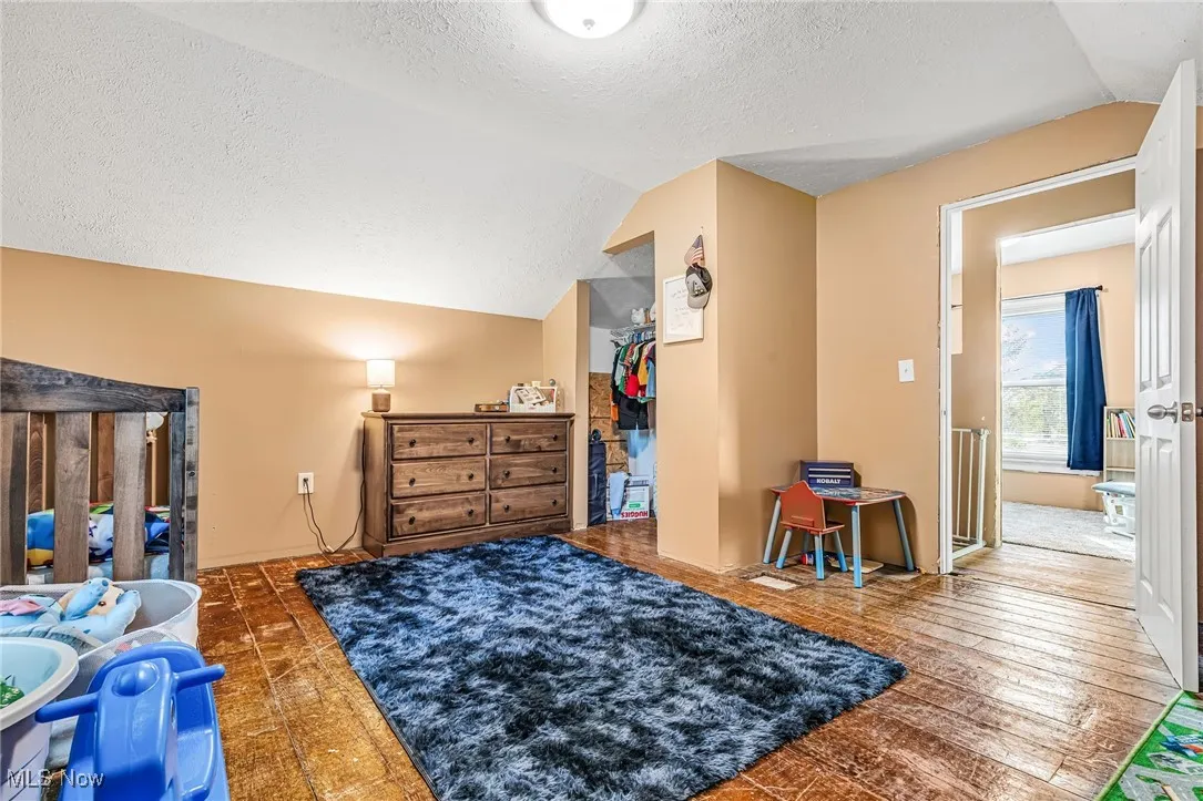 Bedroom# 3 featuring vaulted ceiling, a textured ceiling, a walk in closet, and wood finished floors
