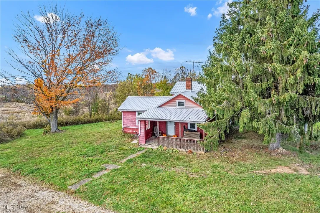 View of front of house featuring a front yard, a metal roof, a chimney, and a porch