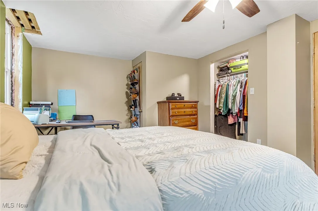Bedroom featuring a ceiling fan and a walk in closet