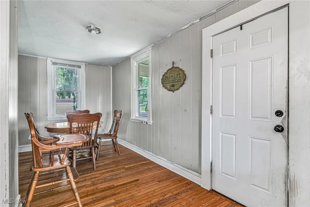 Dining area featuring dark wood-style flooring, a textured ceiling, healthy amount of natural light, and wood walls