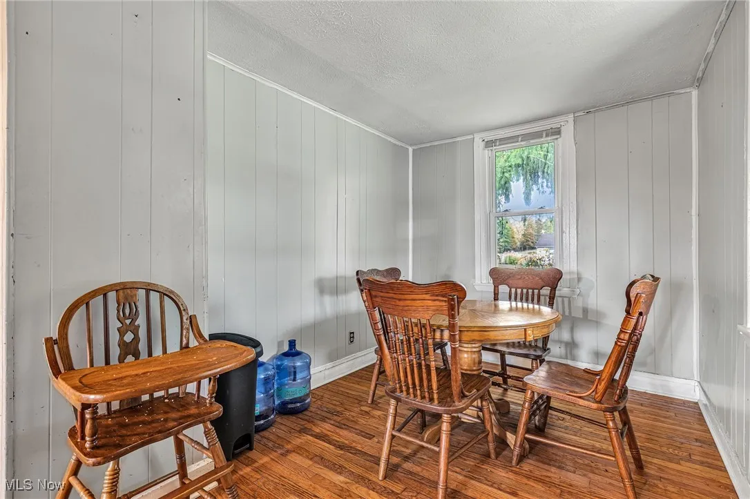 Dining area featuring wood finished floors, a textured ceiling, and wooden walls