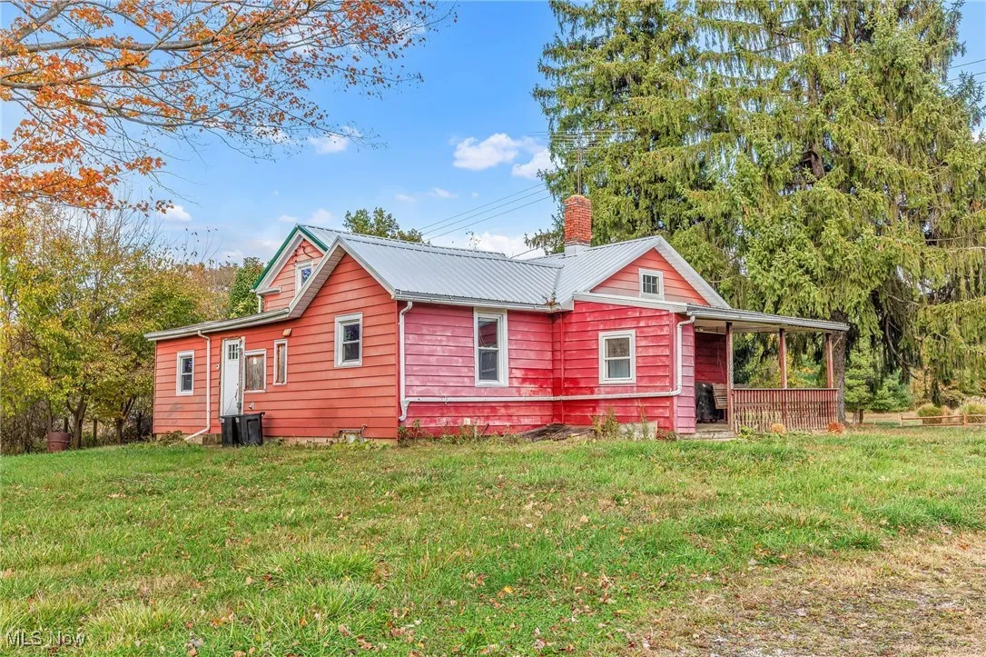 Rear view of house featuring a chimney, a yard, and a metal roof