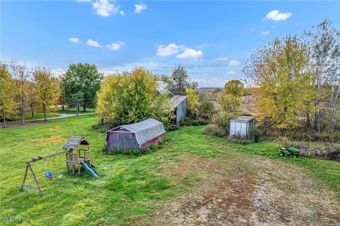 View of grassy yard featuring a playground, a shed, and a rural view