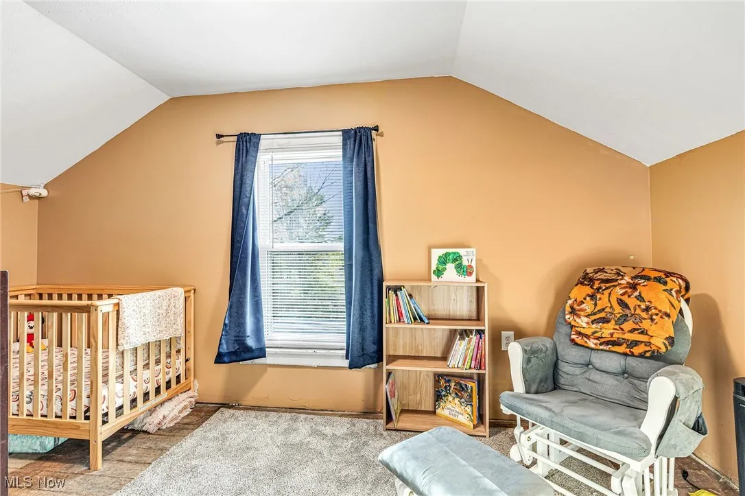Carpeted bedroom #2 with lofted ceiling and a nursery area