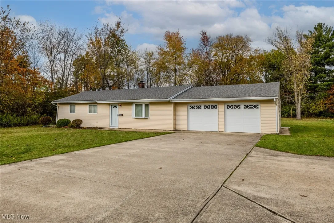 Single story home with a front yard, concrete driveway, a garage, roof with shingles, and a chimney