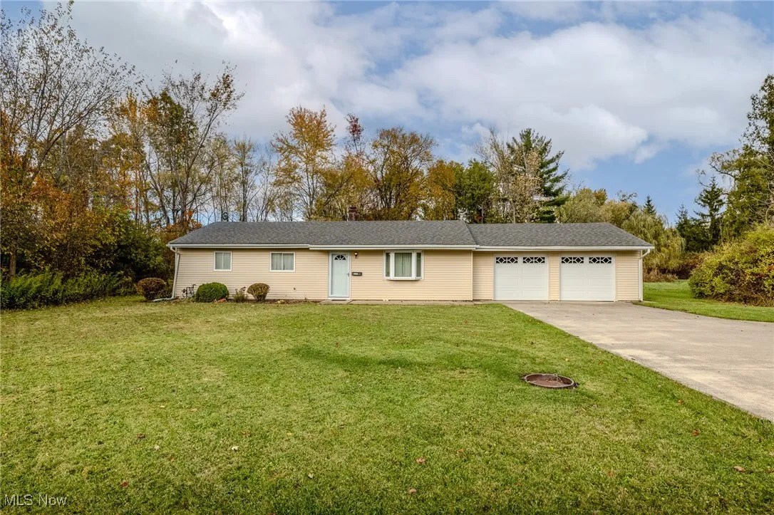 Ranch-style house with driveway, a front yard, and an attached garage