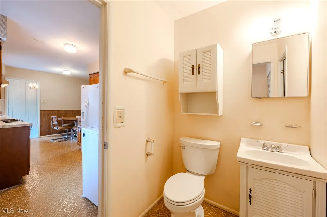 Bathroom with vanity, wainscoting, wood walls, and washer / clothes dryer
