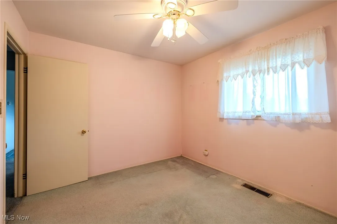 Carpeted empty room featuring ceiling fan