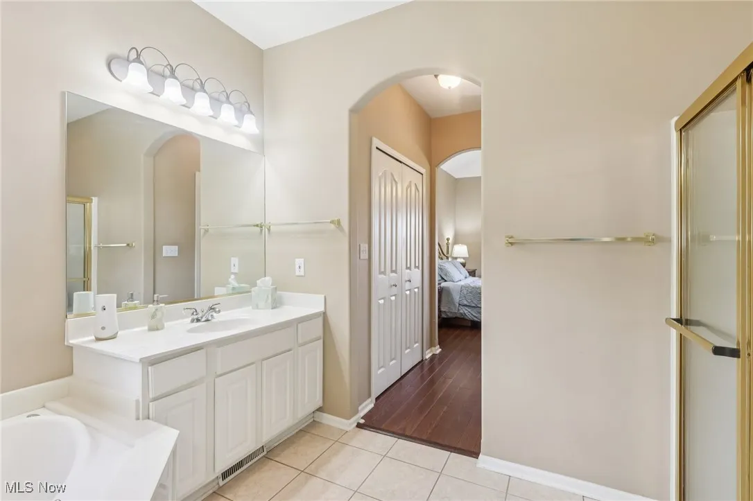 Ensuite bathroom featuring vanity, light tile patterned flooring, a garden tub, and a stall shower