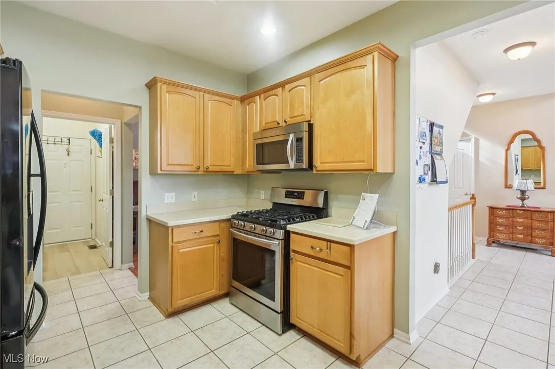 Kitchen featuring appliances with stainless steel finishes, light countertops, light tile patterned floors, and light brown cabinets