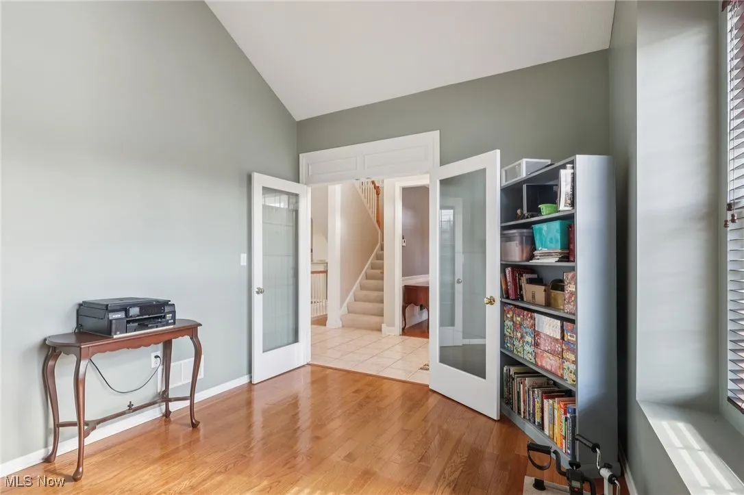 Home office featuring french doors, light wood-type flooring, and lofted ceiling