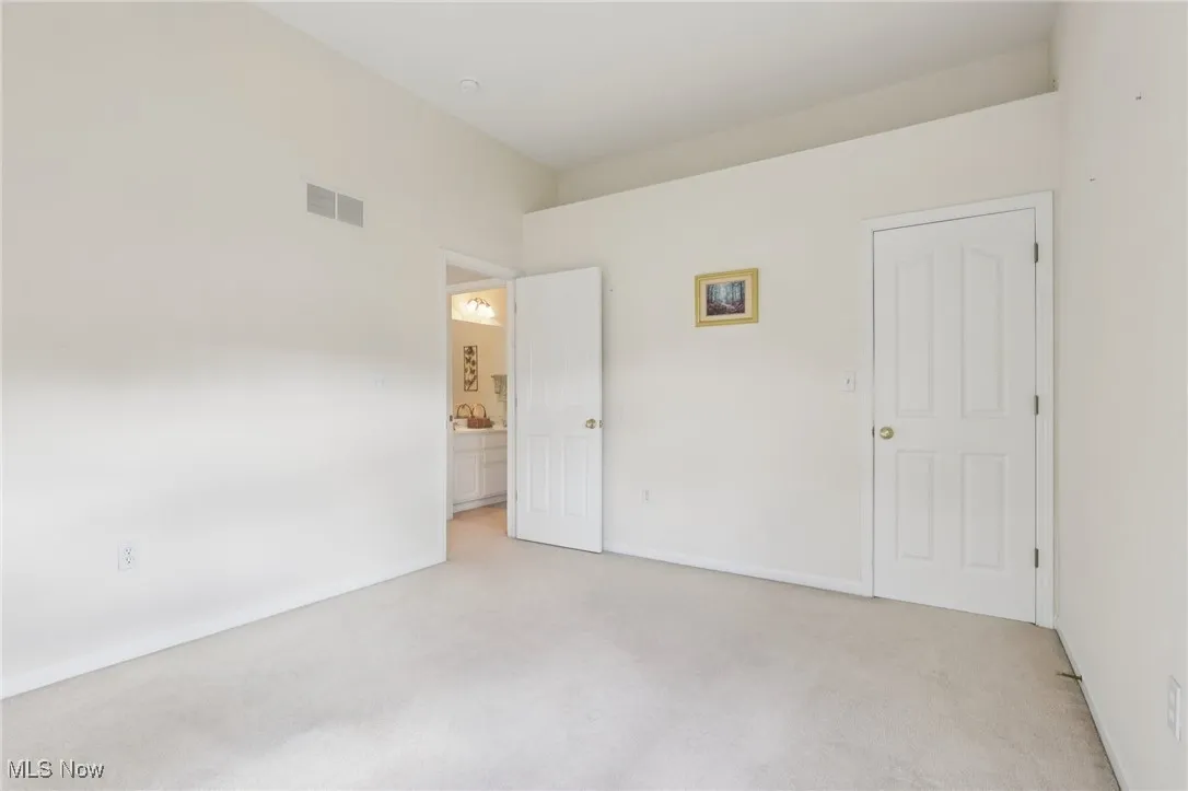 Unfurnished bedroom with light colored carpet and baseboards