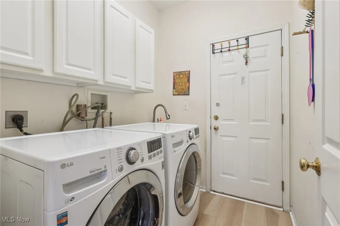 Laundry area with cabinet space, light wood finished floors, and washing machine and dryer