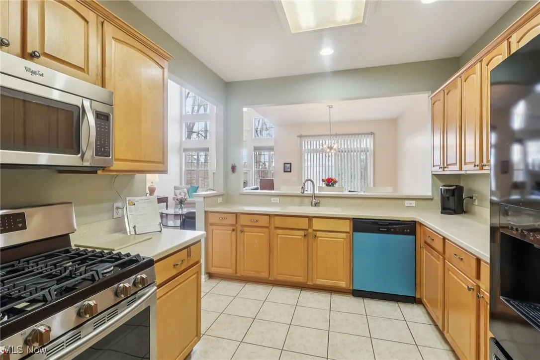 Kitchen with appliances with stainless steel finishes, light tile patterned flooring, pendant lighting, a chandelier, and recessed lighting