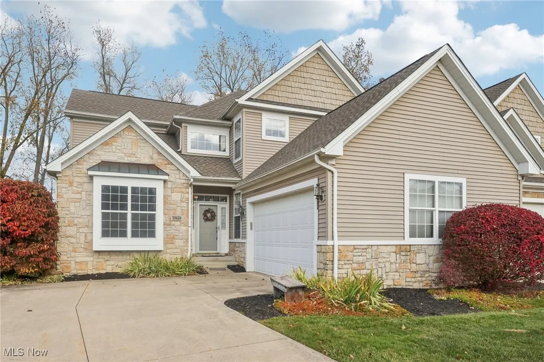 Craftsman house featuring stone siding, a shingled roof, driveway, and a garage