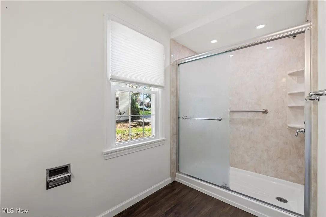 Full bath featuring dark wood-type flooring and a stall shower