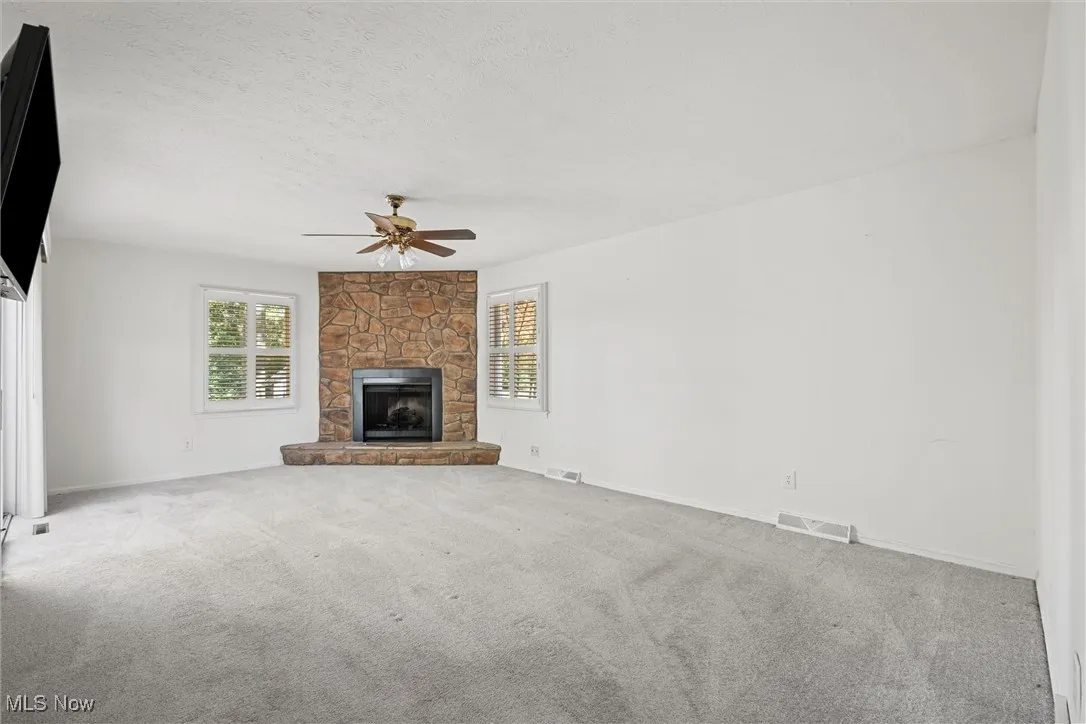 Master Bedroom with carpet floors, a fireplace, a textured ceiling, and ceiling fan