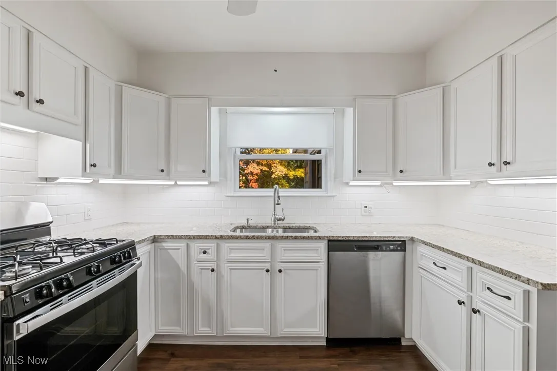 Kitchen featuring appliances with stainless steel finishes, white cabinets, and light stone countertops