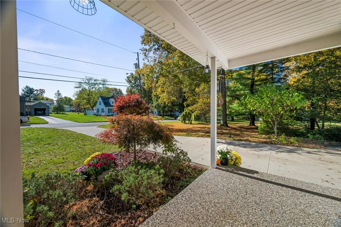 View of green lawn with driveway from front porch