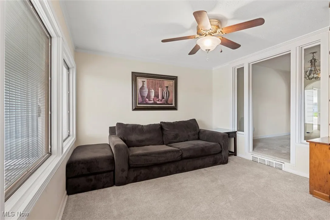 Carpeted  with ornamental molding and ceiling fan