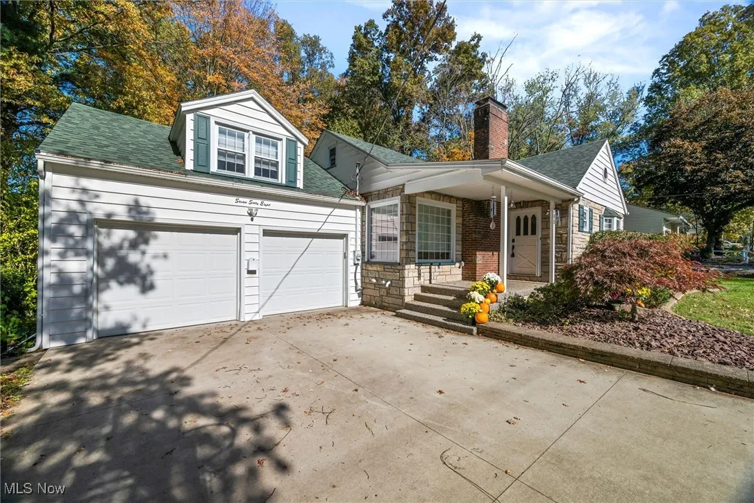 View of front of house featuring covered porch, concrete driveway, a garage, roof with shingles, and a chimney