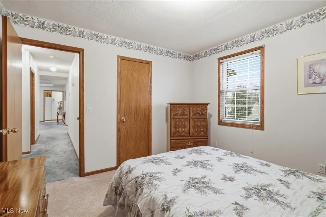 Bedroom with light colored carpet, a closet, and a textured ceiling