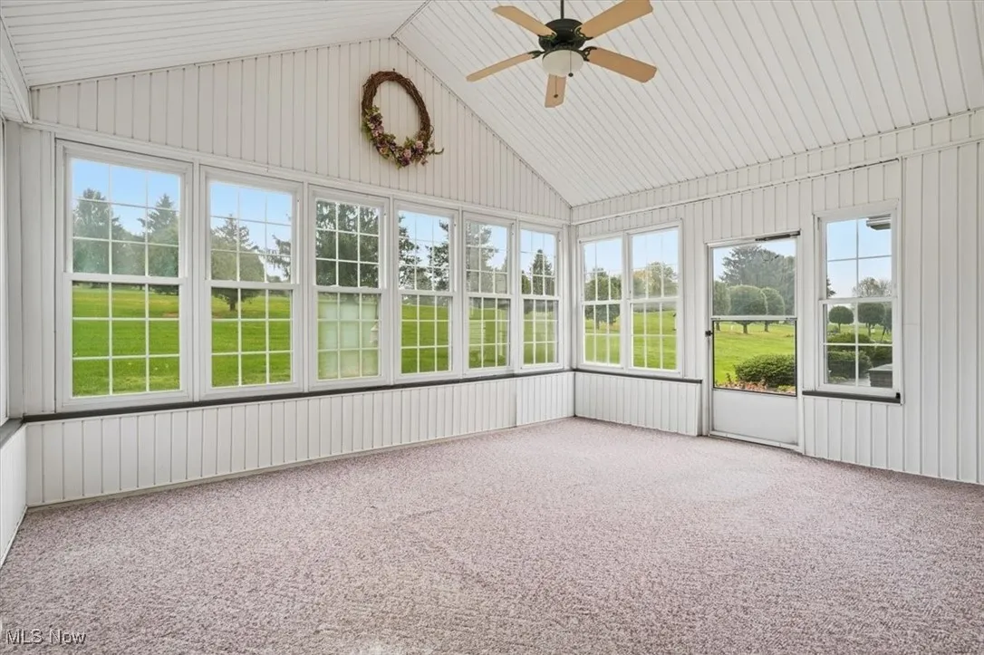 Unfurnished sunroom with lofted ceiling and a ceiling fan